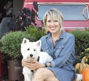 Linda Vater和她的白色Westie狗坐在一辆红色复古皮卡的后面，周围是南方生活植物Pancake Arborvitae爱游戏体育官网注册