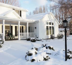 白色的板条住宅，黑色的百叶窗和黑色的灯柱，在白雪覆盖的冬季景观中