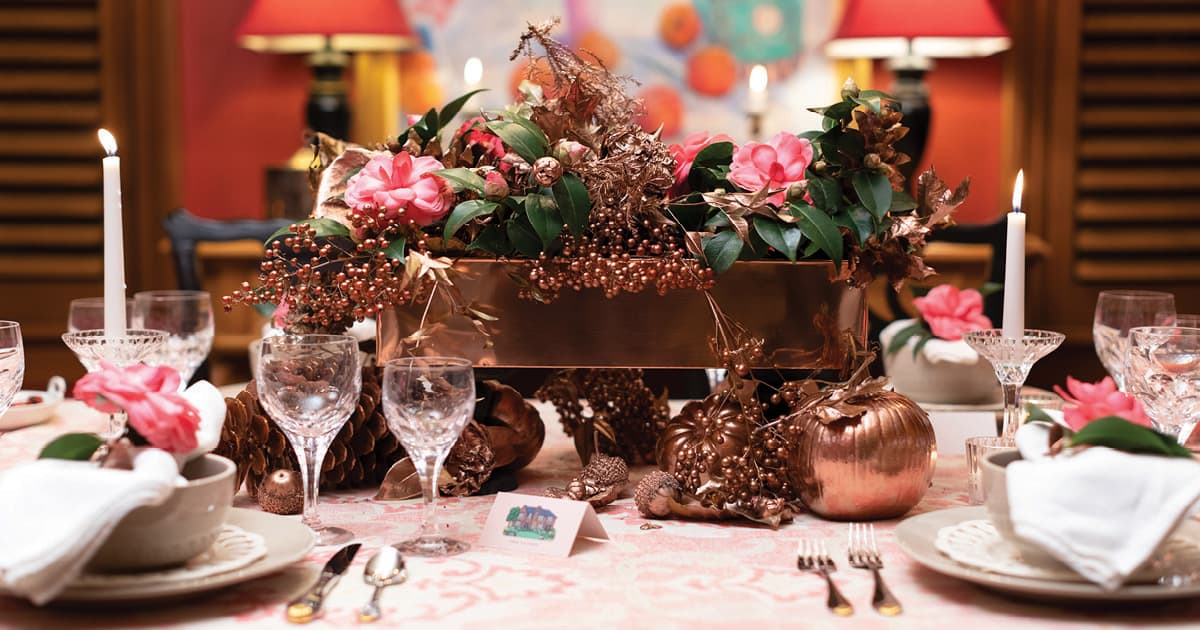 感恩节铜容器，粉红色的玫瑰，奶油色的餐具和白色的蜡烛